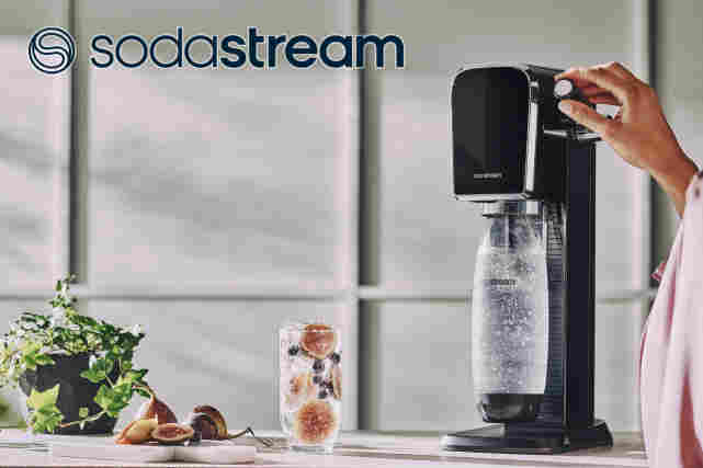 Sodastream-logo. Taustalla keittiönpöytä jossa on Sodastreamillä tehdään juotavaa.