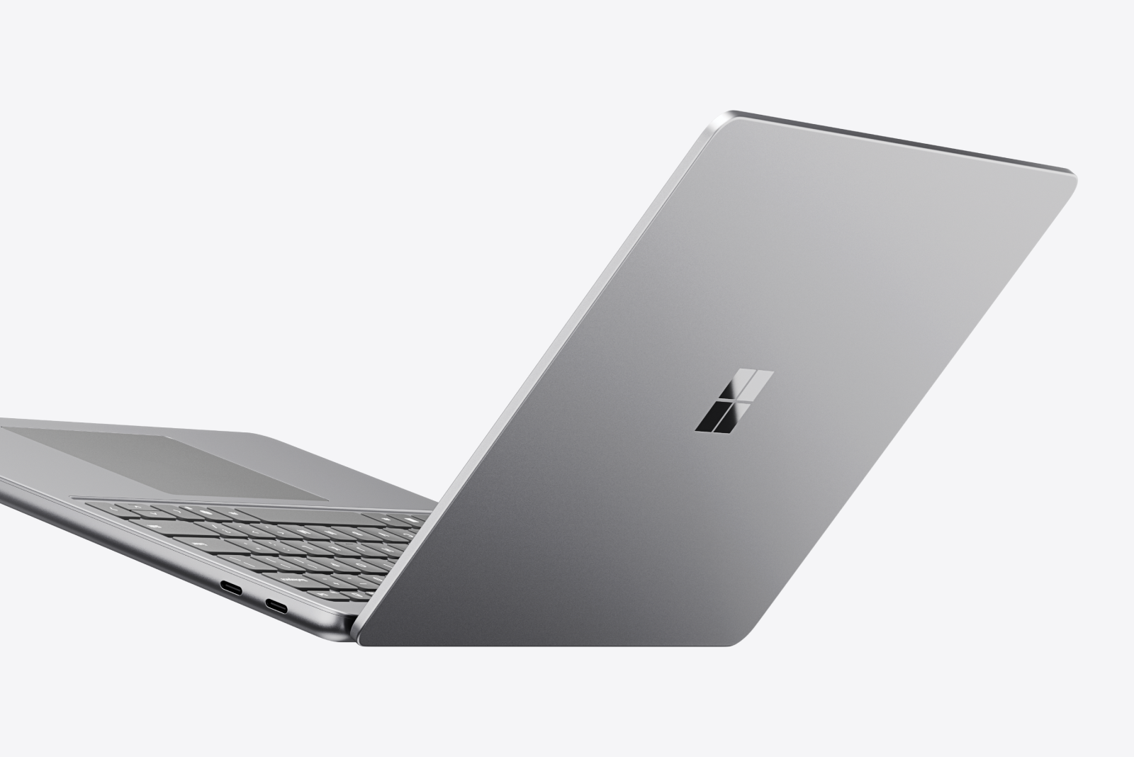 A falling open Surface Laptop against a gray background