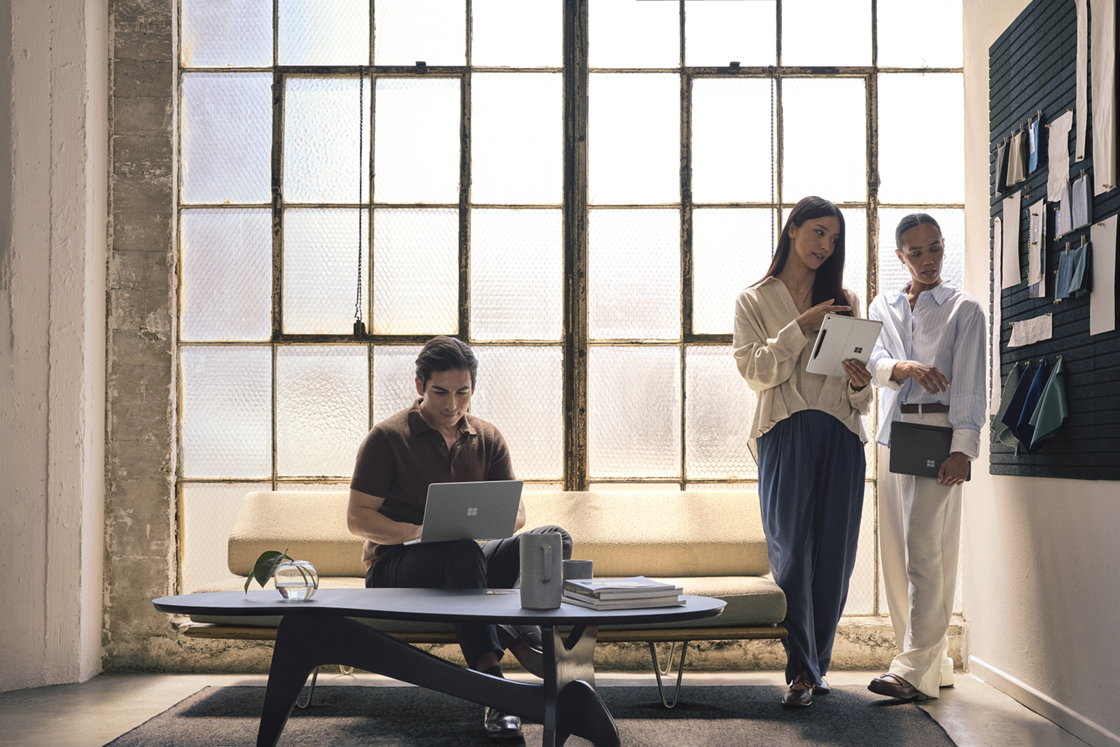 Three professionals working together. One is using a Surface laptop and two are using a Surface Pro.
