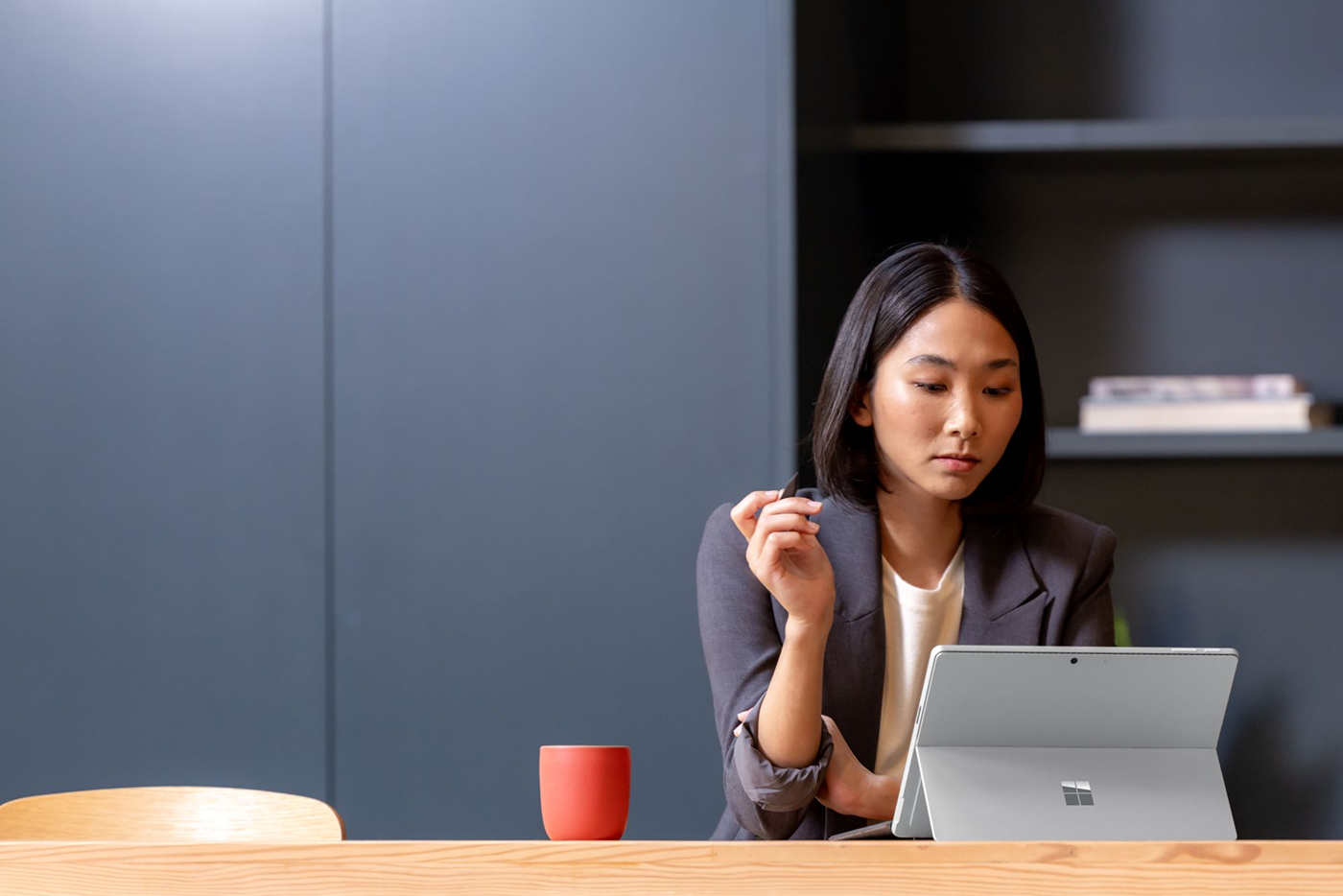 A woman works on a Surface Pro while sitting at a table