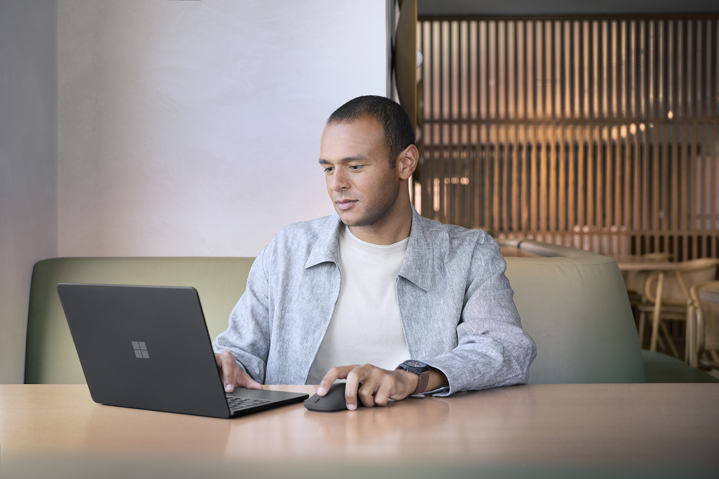 A man sitting at an office desk working on a Surface Laptop