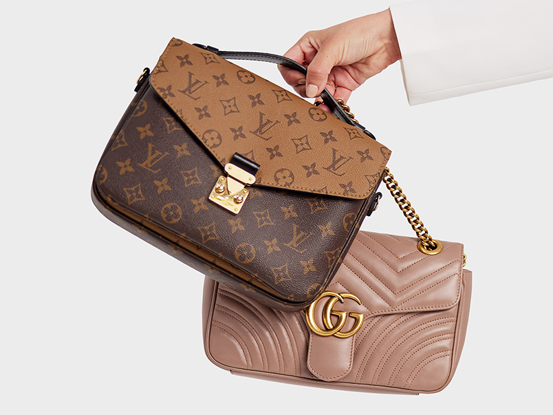 Hand holding Louis Vuitton and Gucci handbags