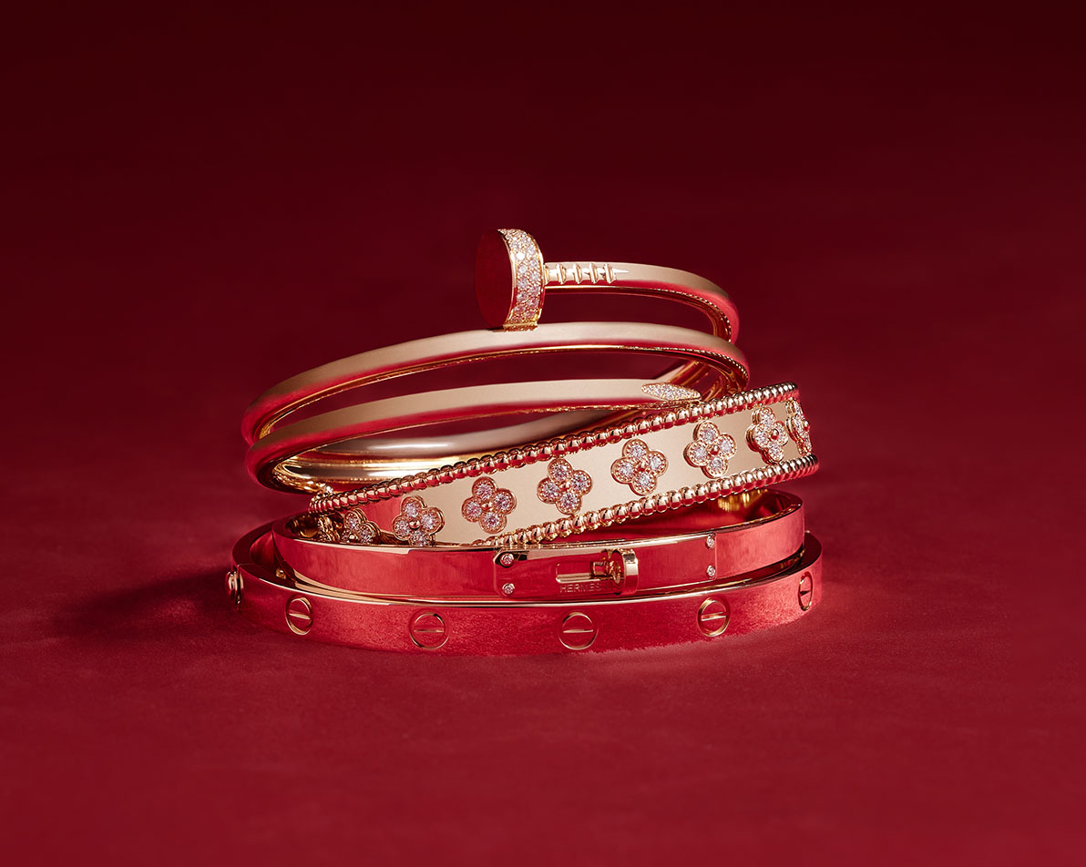 one rose gold Cartier double wrap Juste Un Clou diamond pave bracelet, one Van Cleef rose gold perlee bangle bracelet, one Hermes rose gold bangle bracelet and one rose gold Cartier Love bracelet all stacked on each other