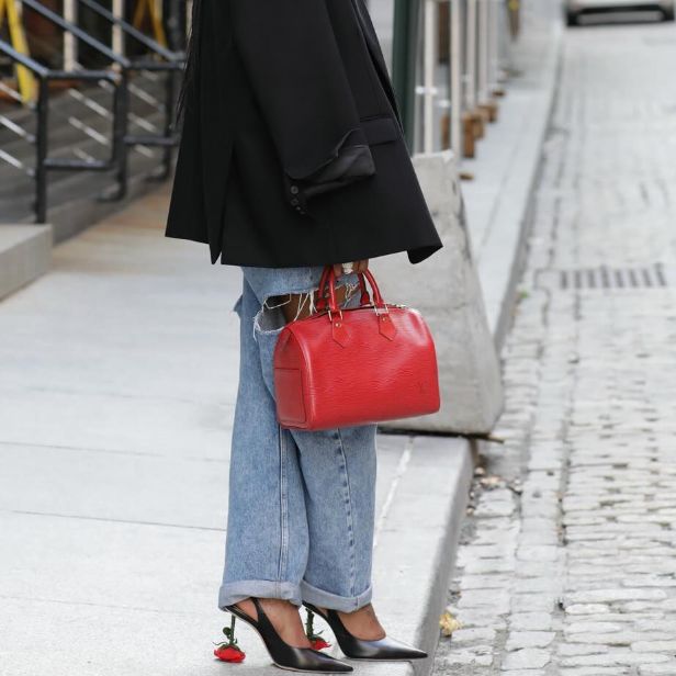 women in denim jeans and black blazer holding a red Louis Vuitton epi Speedy