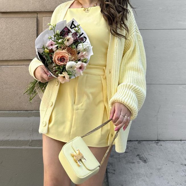 a woman in a yellow dress and yellow sweater holding a yellow Celine Triomphe bag