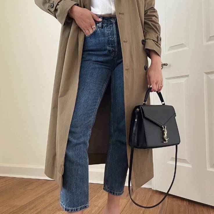 woman in denim pants and a khaki coat holding a black Saint Laurent Cassandra Top Handle