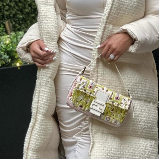 woman in white long dress and white coat holding a white beaded Fendi Baguette