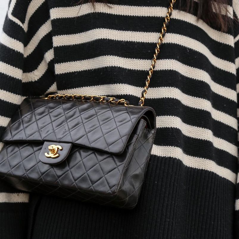 woman in striped black and white sweater wearing a black Chanel single flap