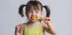 Criança com escova de dente na boca