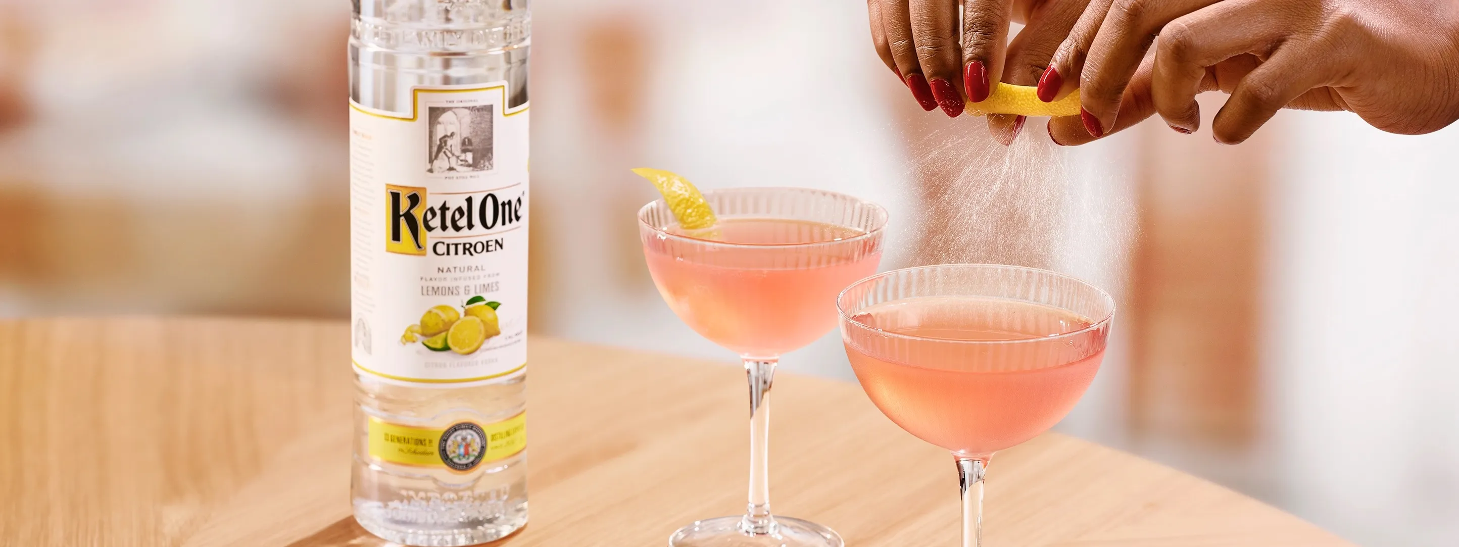 Ketel One Cosmo in Coupe Glass with hand adding lemon spritz