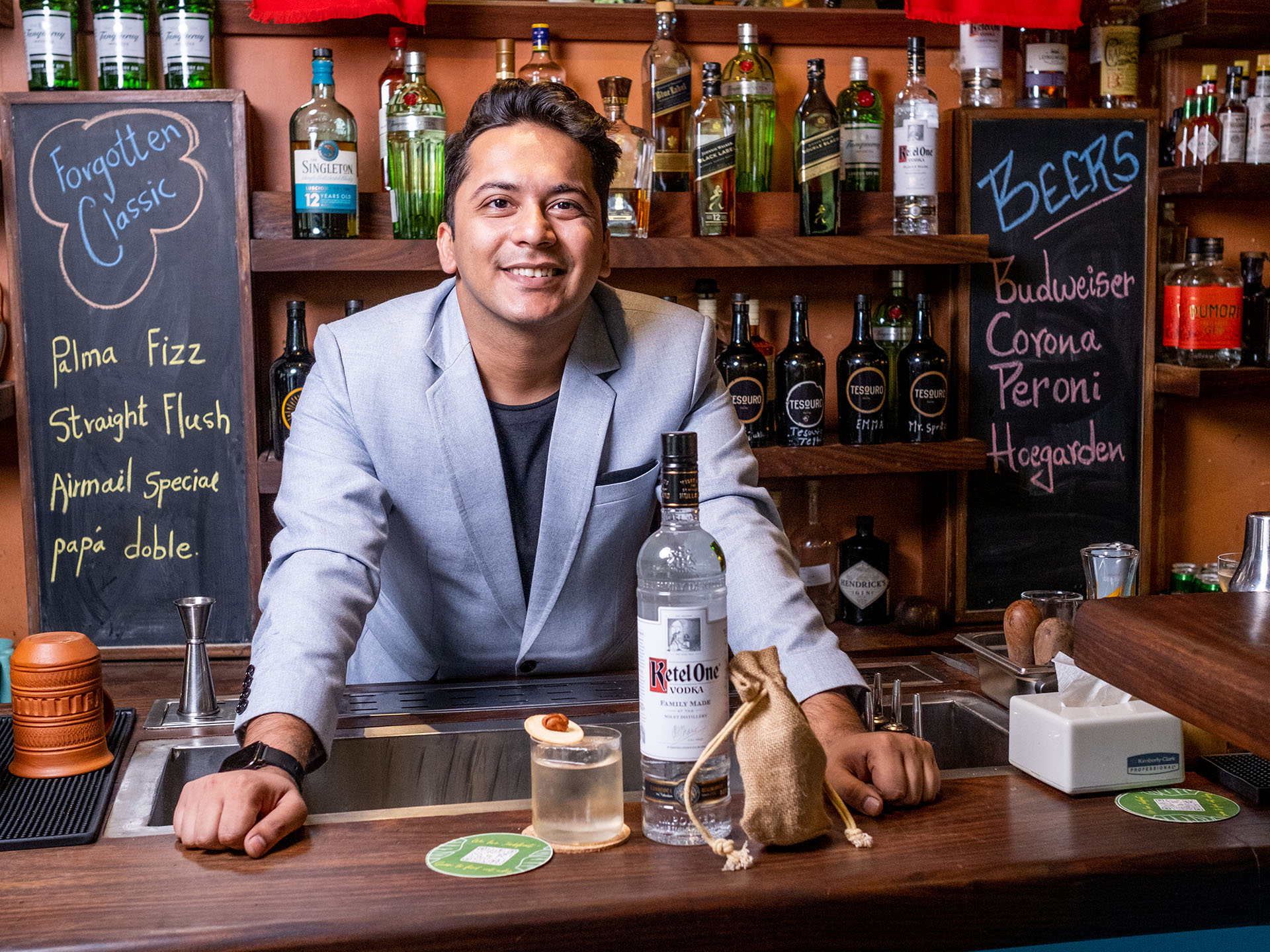 Sahil Essani standing in a bar with Ketel One Vodka and a cocktail