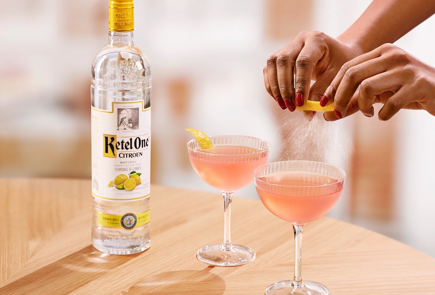 Cosmo Ketel One dans une coupe, une personne pressant un zeste de citron