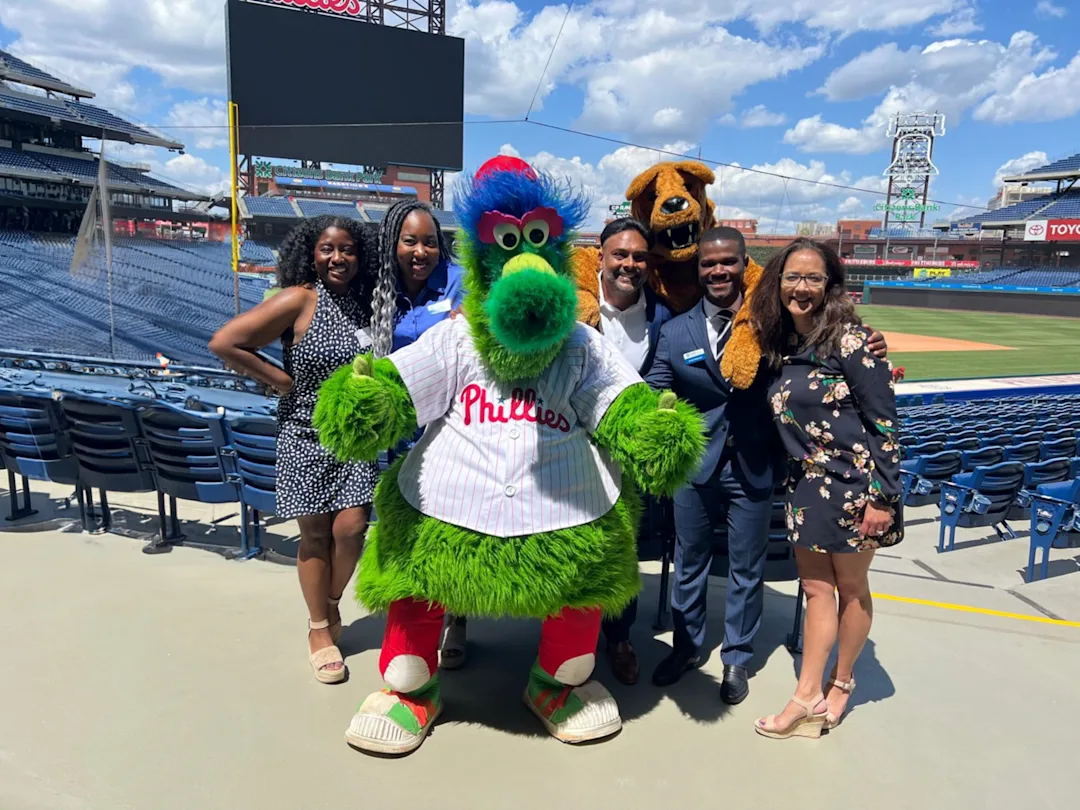 Penn State staff with Phillies team mascot in baseball stadium