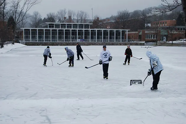 Photo of students playing ice hockey on campus pond