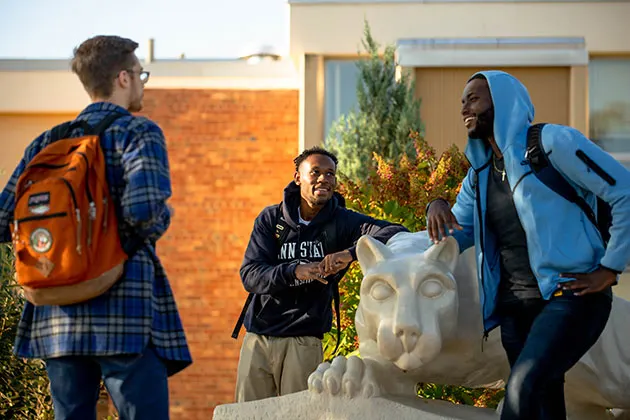 Three students talking around lion shrine