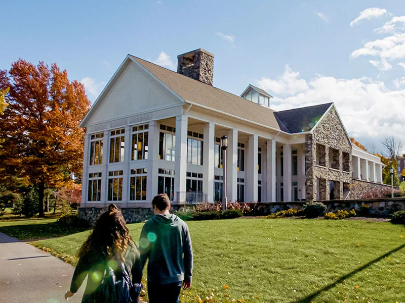 People walking by a large white columned building at Penn State Behrend.