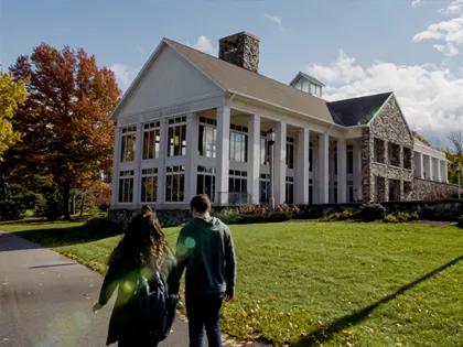 People walking by a large white columned building at Penn State Behrend.