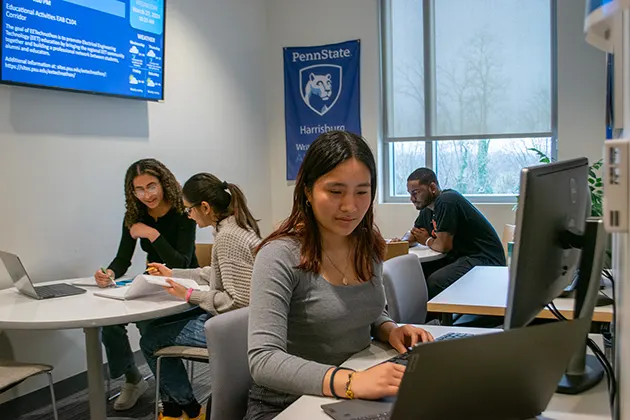 A room of four students in varying states of group and independent study.