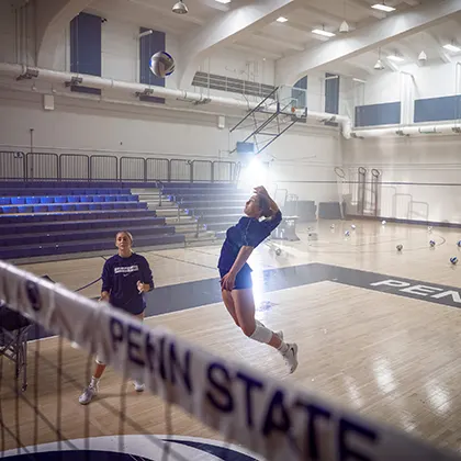 A volleyball player jumping in the air about to spike a ball