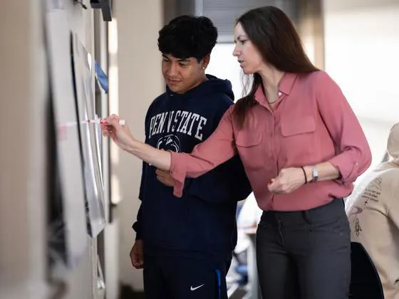 Photo of a student and instructor writing on a marker board together