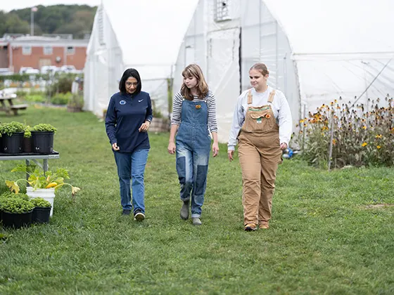 Neeli Bendapudi walking with two students at a farm