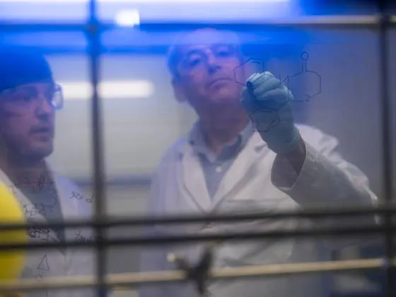 Photo of two people writing on a marker board