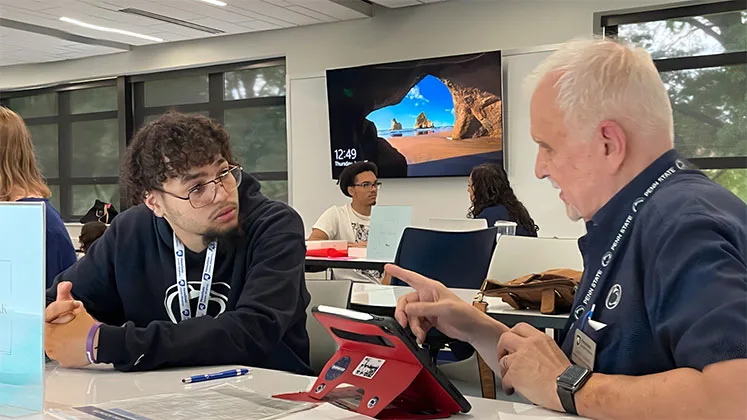 Photo of a student and instructor working together on a tablet in a classroom