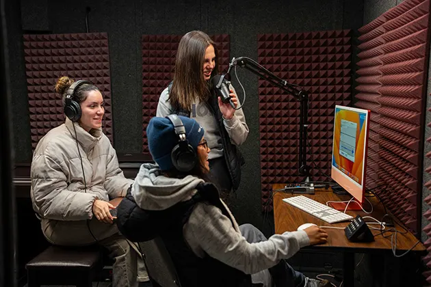 Three students recording in a soundproof studio.