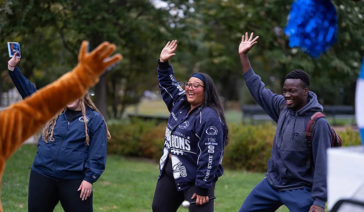 Three people dancing with arms raised in the air.