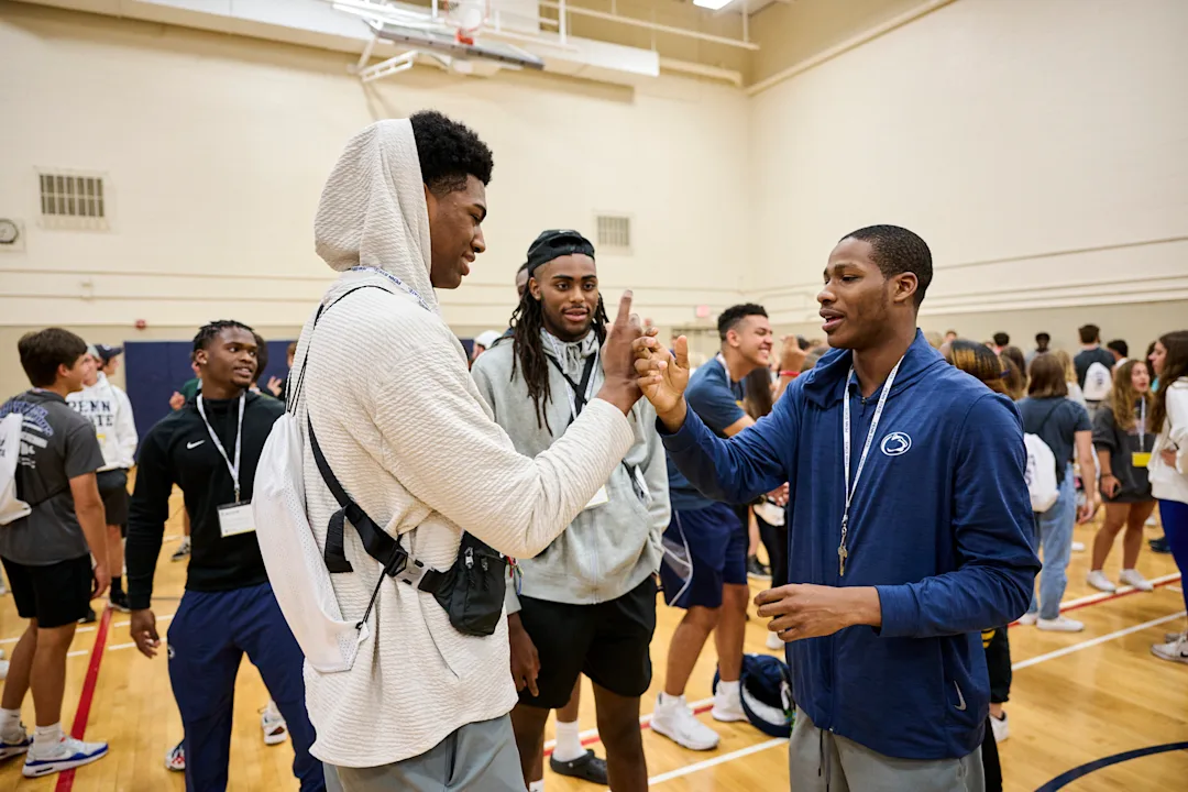 Three students greeting each other inside basketball court