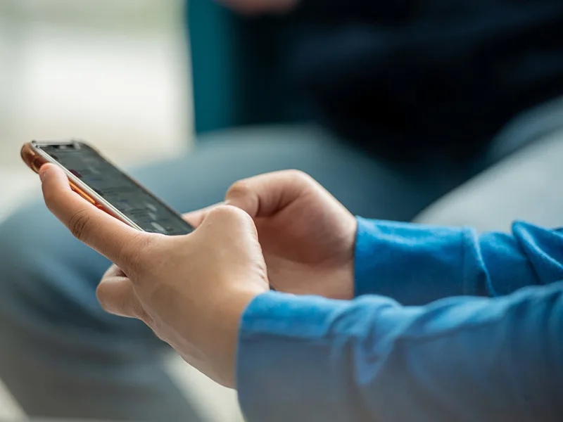 Photo of a student's forearms and hands holding a cell phone