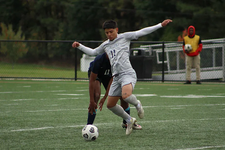 Photo of a Penn State Beaver men's soccer player dribbling in a game
