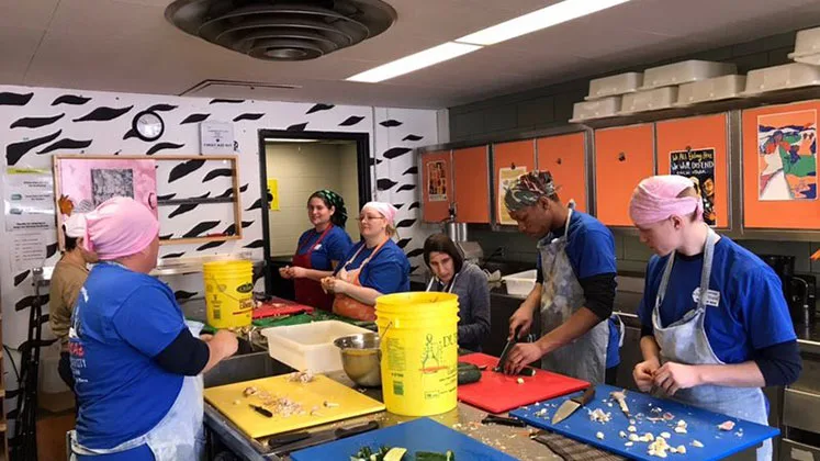 Photo of students chopping vegetables together in an industrial kitchen