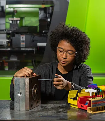 Photo of a student interacting with a machine in the Plastics Training Lab