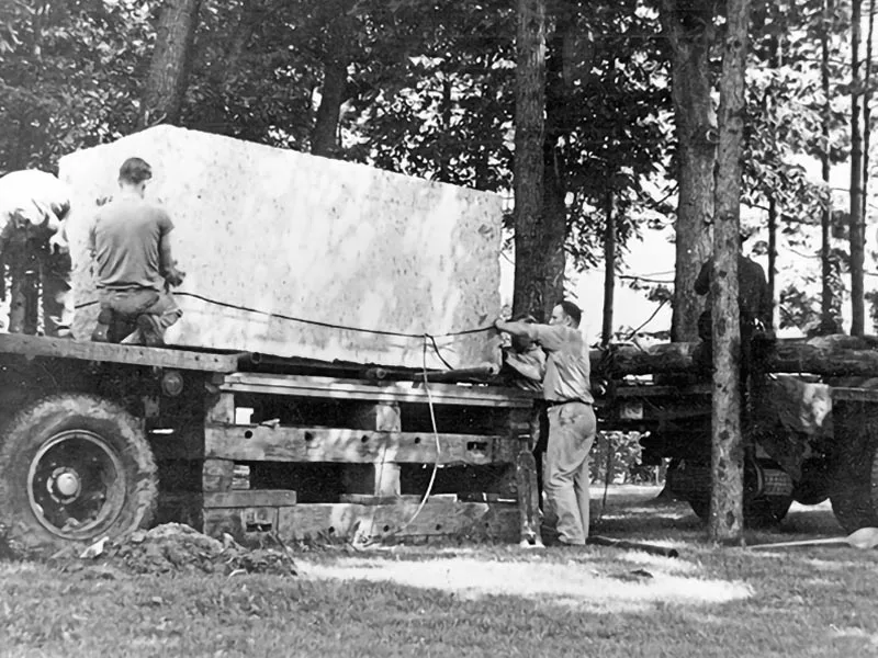 The Indiana limestone block for the Nittany Lion Shrine is unloaded off of the truck and onto a wooden platform.