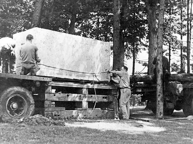 The Indiana limestone block for the Nittany Lion Shrine is unloaded off of the truck and onto a wooden platform.