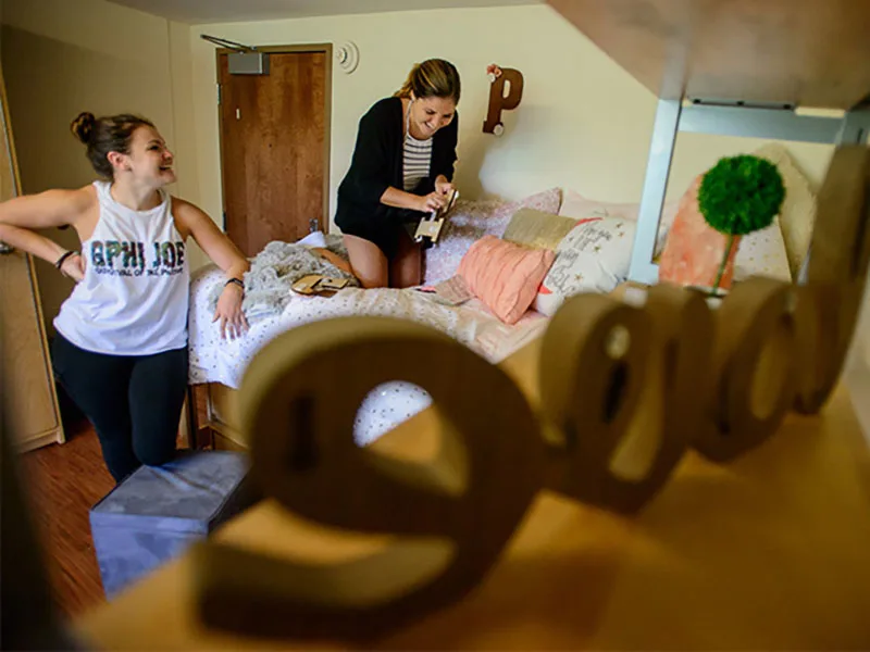 Two students laughing as they unpack in their new dorm room