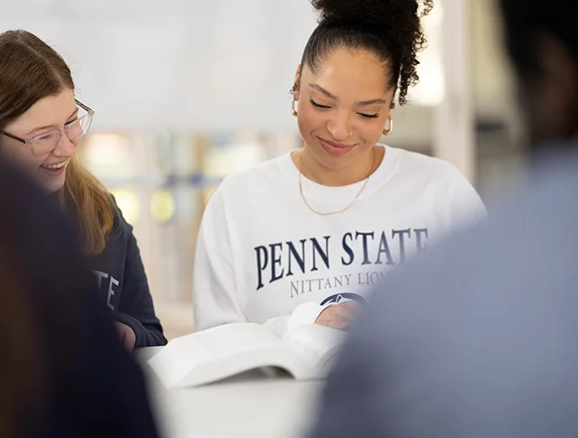 Female student in Penn State gear participating in a study session with a student group.