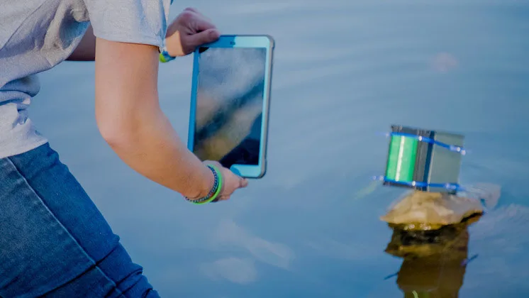 Photo of a student photographing their research project in a pond