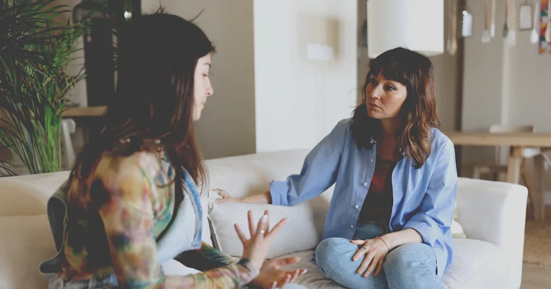 Two people having a conversation in a home. 