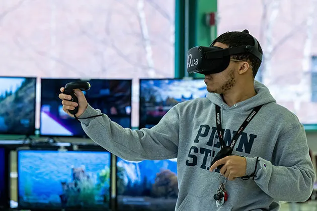 Photo of a student standing, wearing a headset in a VAR lab