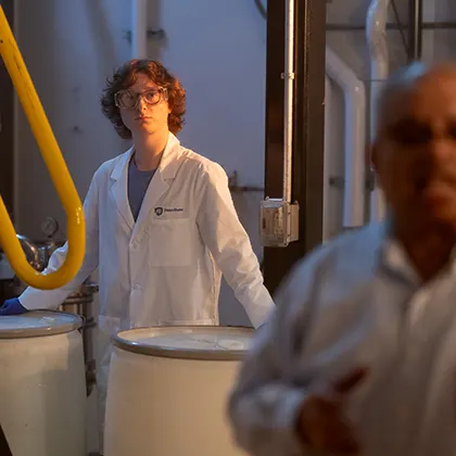 A student in a research lab surrounded by large barrels