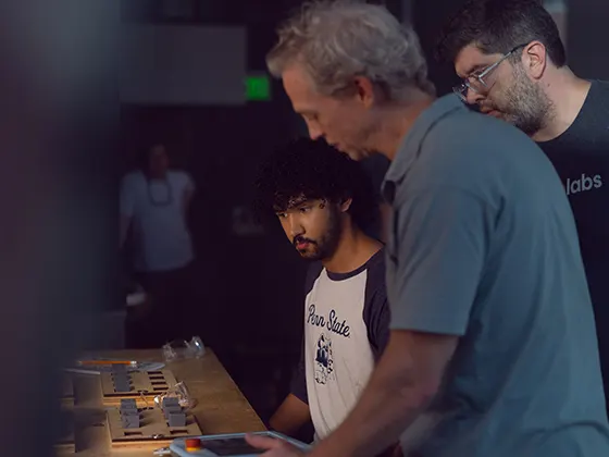 Three people looking over an board of plugs on a table