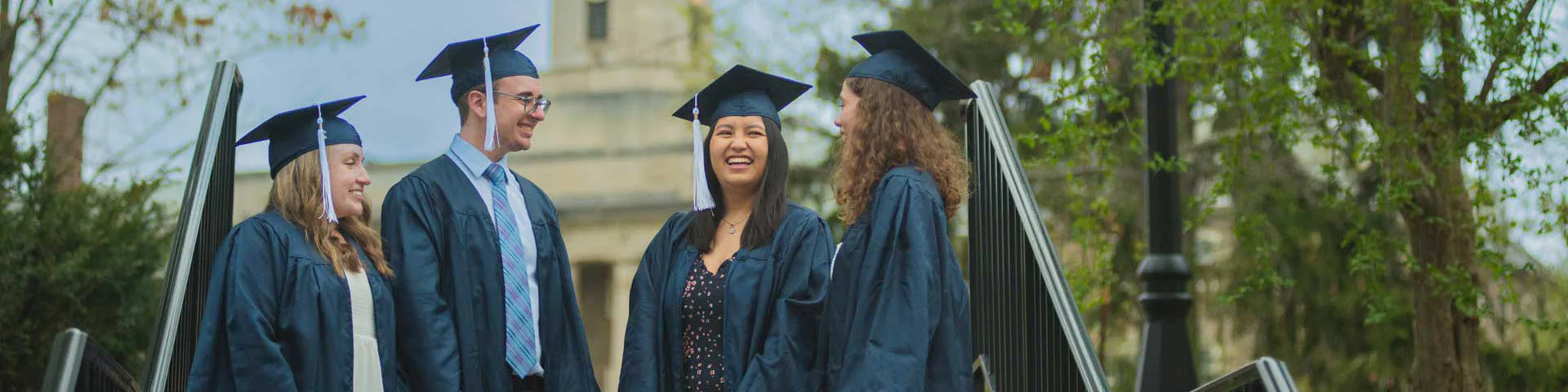 Photo of students in graduation gowns standing in front of Old Main