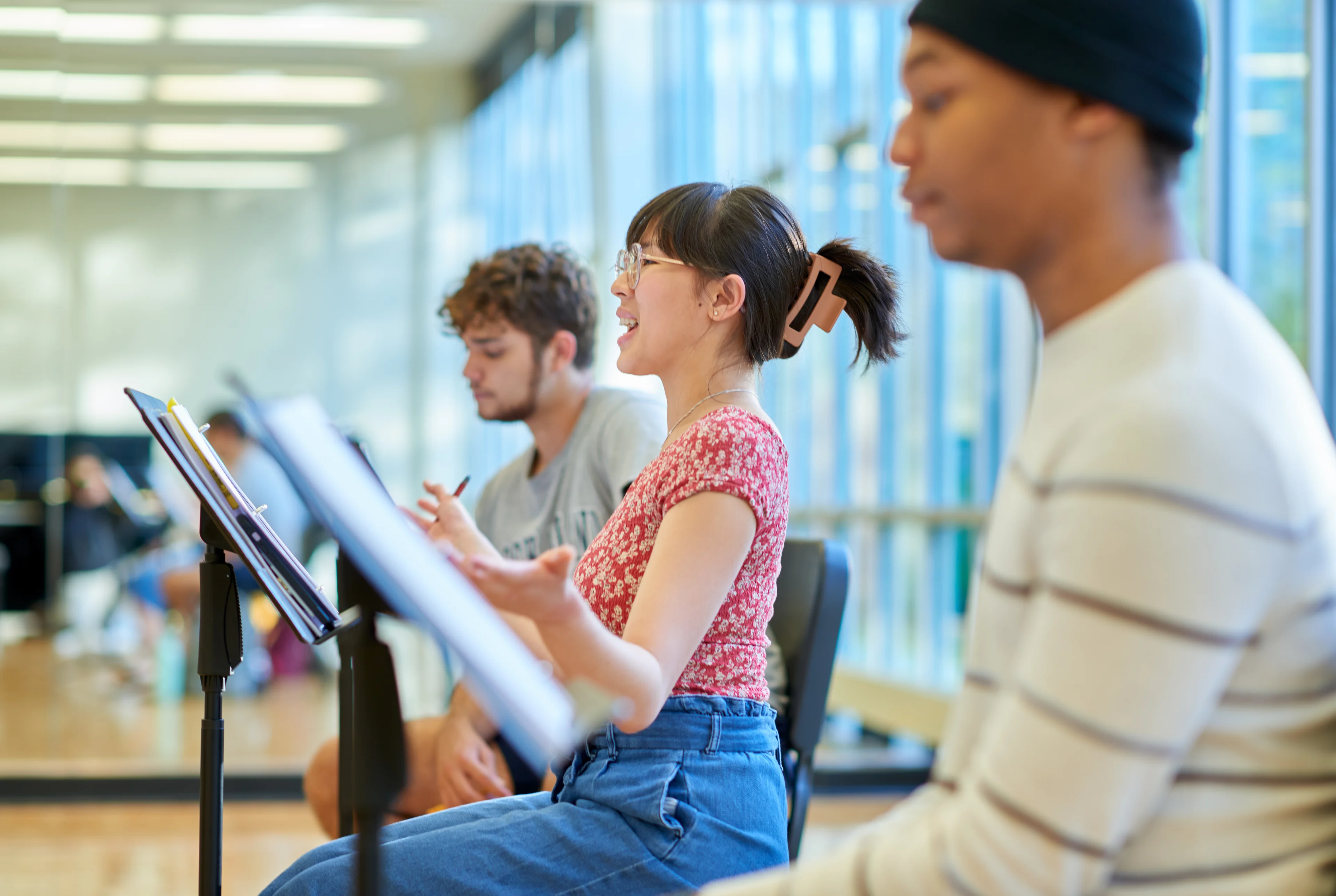 Three students sitting in front of music stands