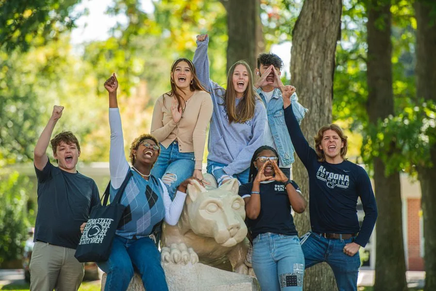 Seven students cheering around a Nittany Lion Shrine replica at Penn State Altoona
