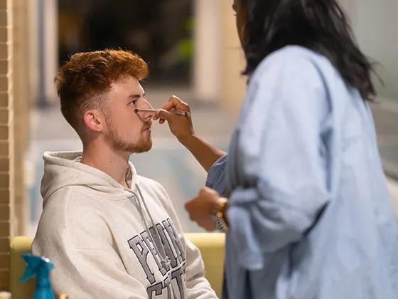 An actor getting their makeup done with a powder brush