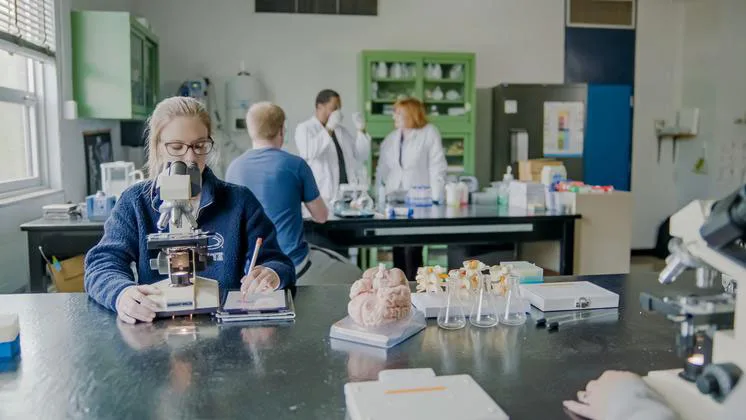 Photo of a lab with a student using a microscope in the foreground