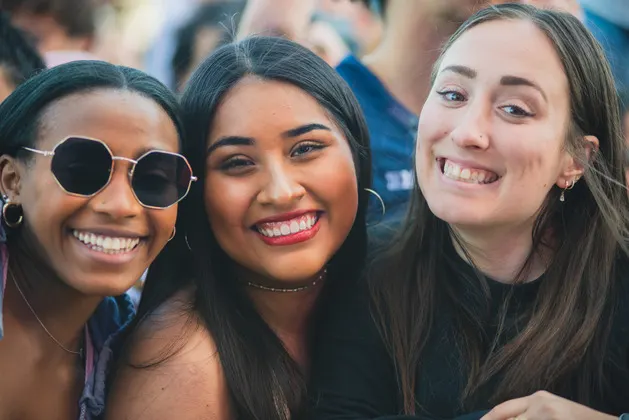 Photo of students in a crowd smiling at the camera