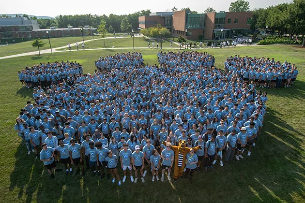Aerial photo of students and the Nittany Lion mascot grouped together to form a paw print
